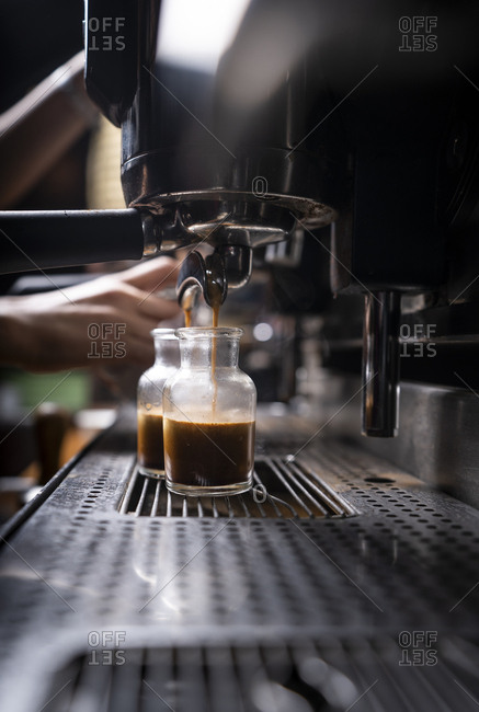 Crop hands of man making coffee by automatic professional equipment in cafe