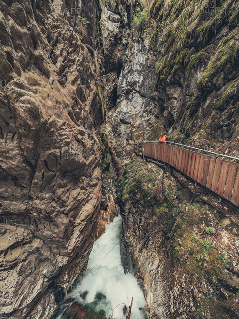 Hiker admiring majestic view of Alps while walking on footbridge in Dolomites, Italy