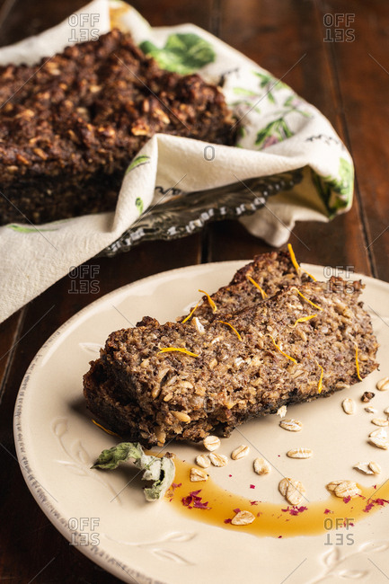 From above brown tasty cake with raw flakes on white plate on wooden background