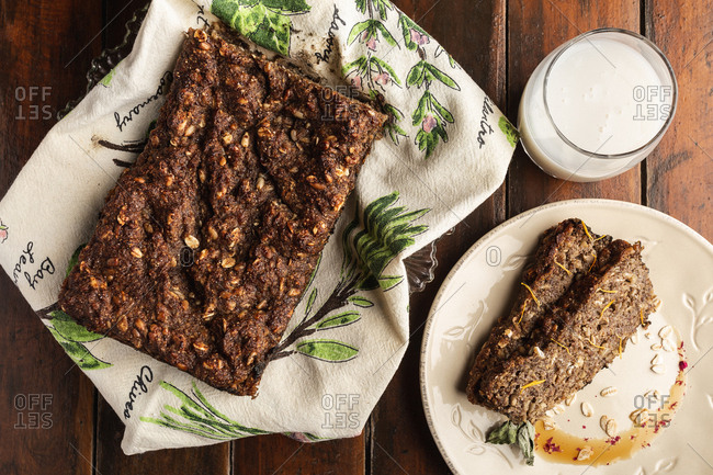 From above brown tasty cake with raw flakes on white plate on wooden background