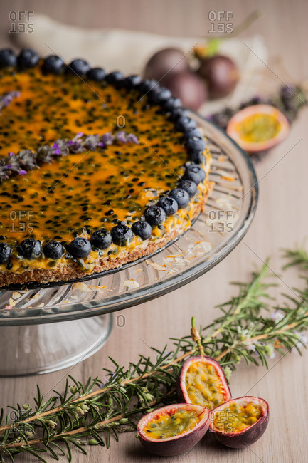 From above appetizing fragrant passion fruit pie with blueberry topping on wooden background decorated with bunch of lavender