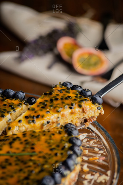 From above piece of appetizing fragrant passion fruit pie with blueberry toppings on wooden background