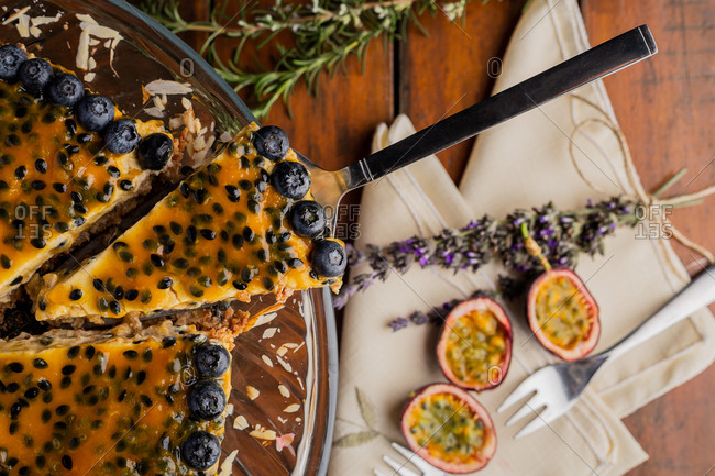 From above piece of appetizing fragrant passion fruit pie with blueberry toppings on wooden background