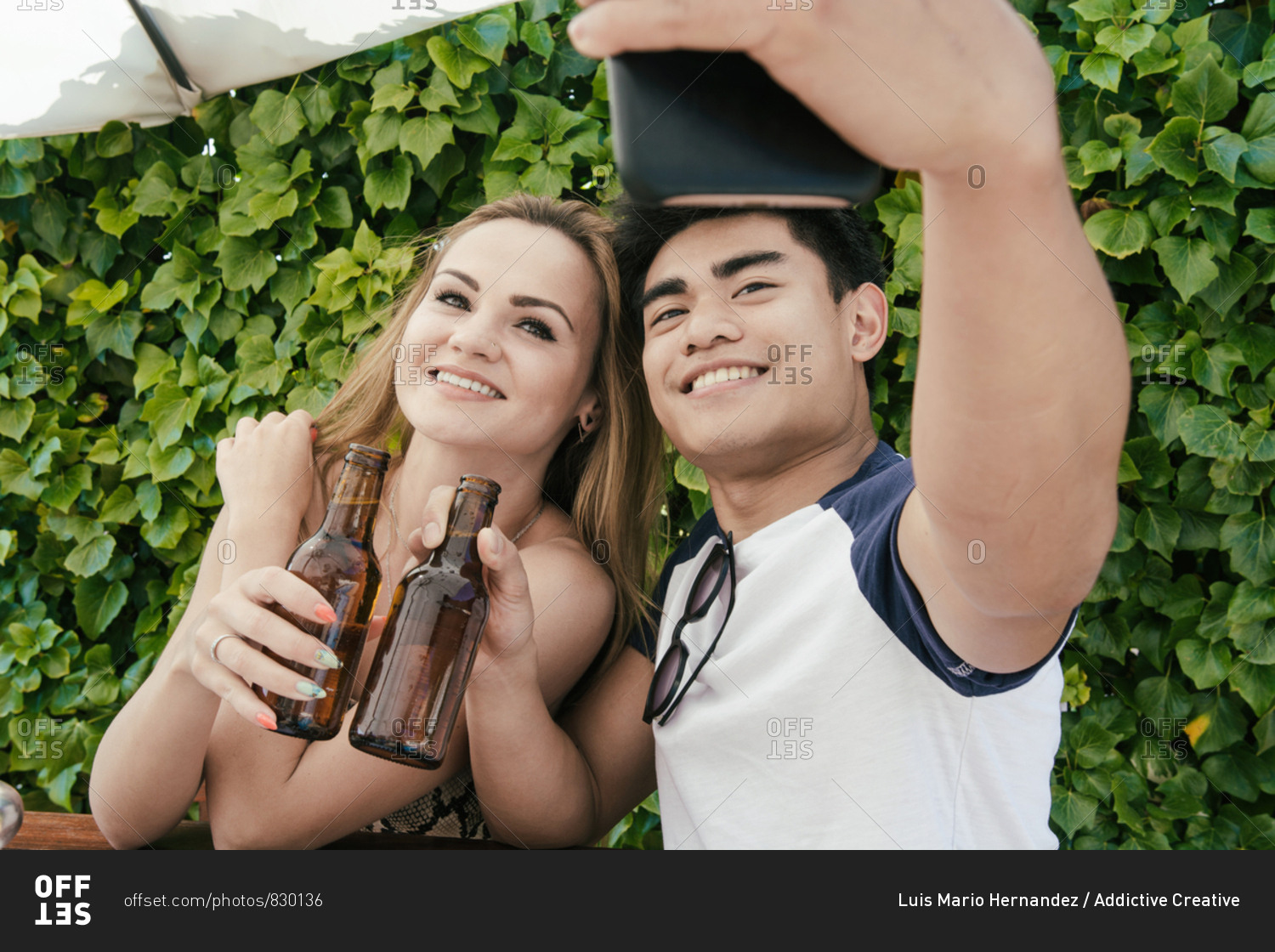 Young couple drinking beer on a sunny day on the terrace of a bar