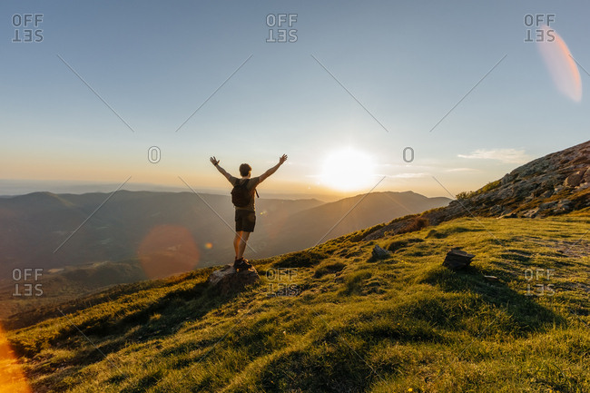 Back view of young man with back pack contemplating amazing mountain landscape on the countryside