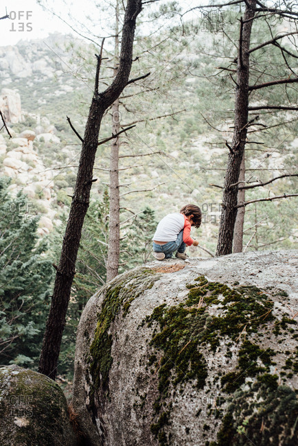 Little curious kid walking down rocky hillside exploring nature