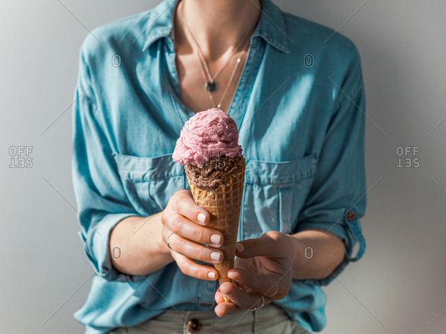 Hand holding ice cream in cone. Ice cream scoop in cone in woman hands