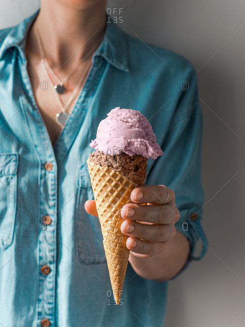 Hand holding ice cream in cone. Ice cream scoop in cone in woman hand. Vertical