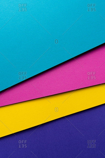 From above layout of colorful cardboard sheets in blue, purple, pink and yellow shades