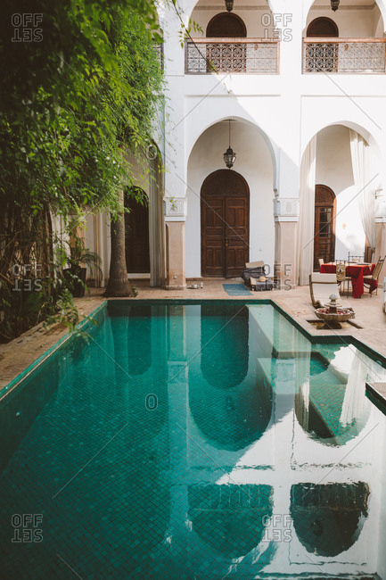 June 25, 2019: Peaceful clear water of pool on terrace of exotic resort with oriental architecture in sunlight, Morocco