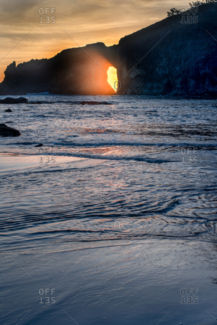 Sunlight passing through hole in a cliff at sundown