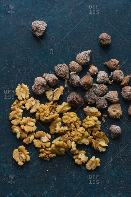 Dried walnuts and small figs on blue background