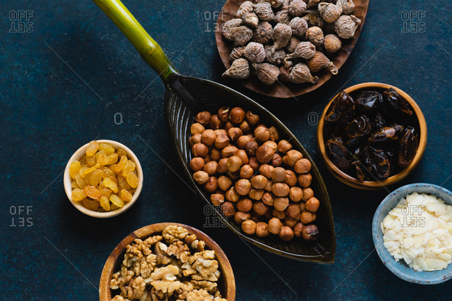 Bowls filled with various nuts and dried fruits: hazelnuts, walnuts, raisins