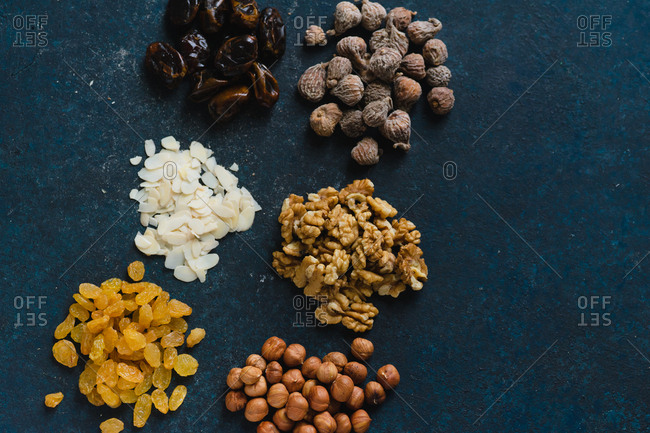 Various nuts and dried fruits: hazelnuts, walnuts, raisins on dark blue background