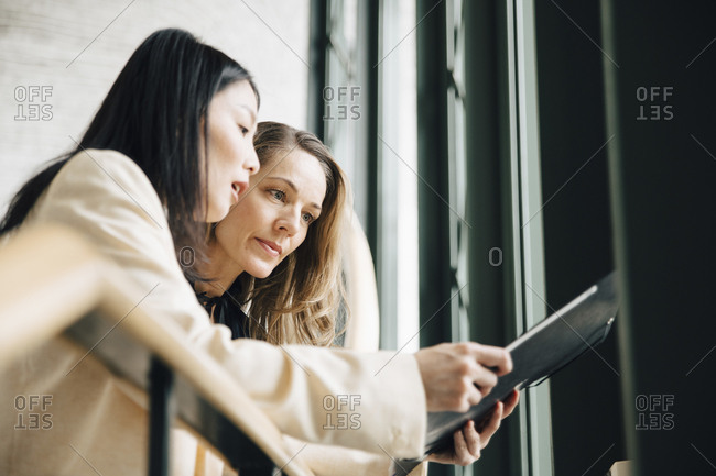 Low angle view of businesswoman discussing with colleague over document at office