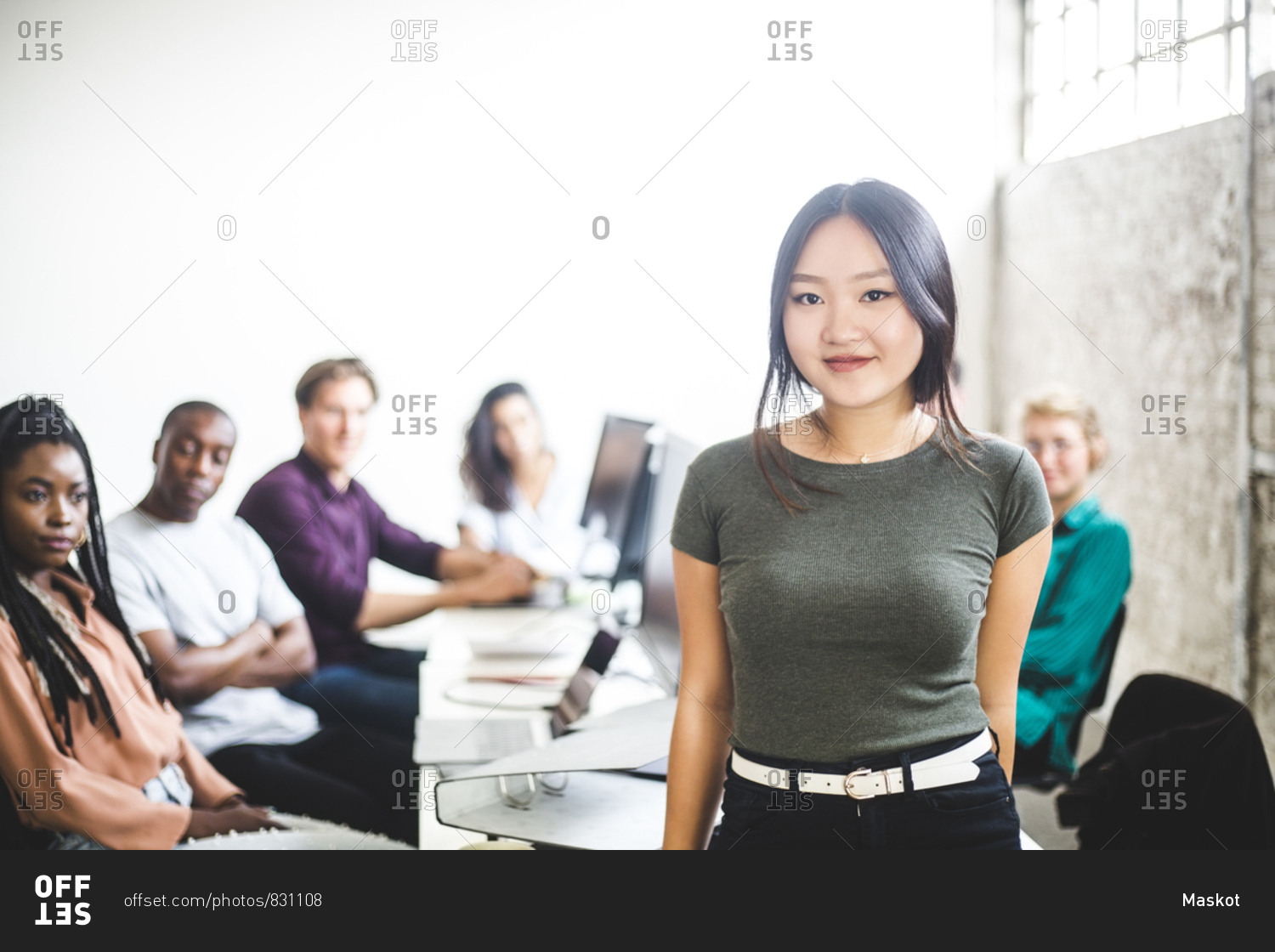 Portrait of smiling female IT expert with coworkers in background at workplace