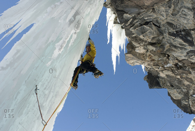 A professional male climber ascends a frozen waterfall pillar while ice climbing near Ouray, Colorado.