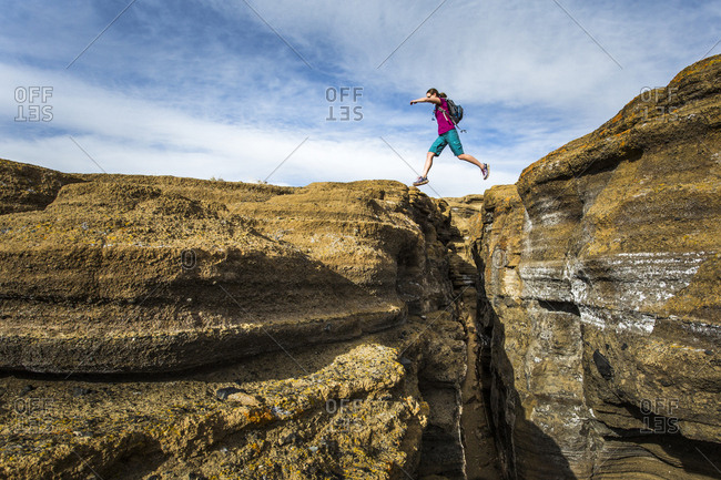 MONO LAKE, CA, USA. A young woman leaps over a deep slot canyon.