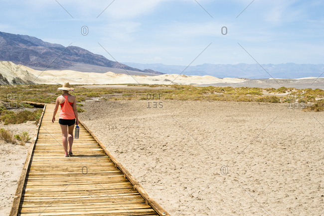 Young female adult walks down walkway in the desert