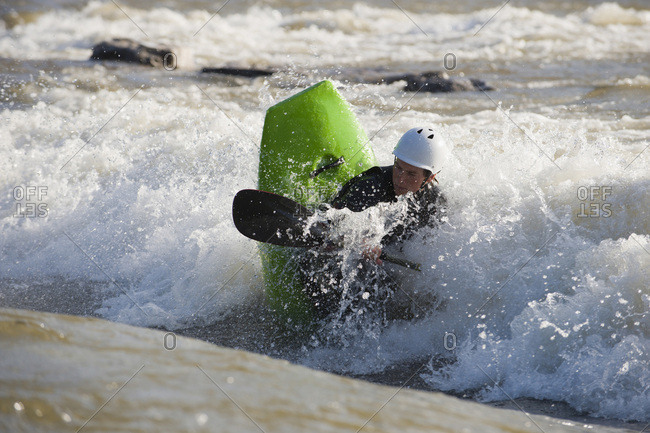 A young male whitewater kayaker playboats on the Clark Fork River, Missoula, Montana.