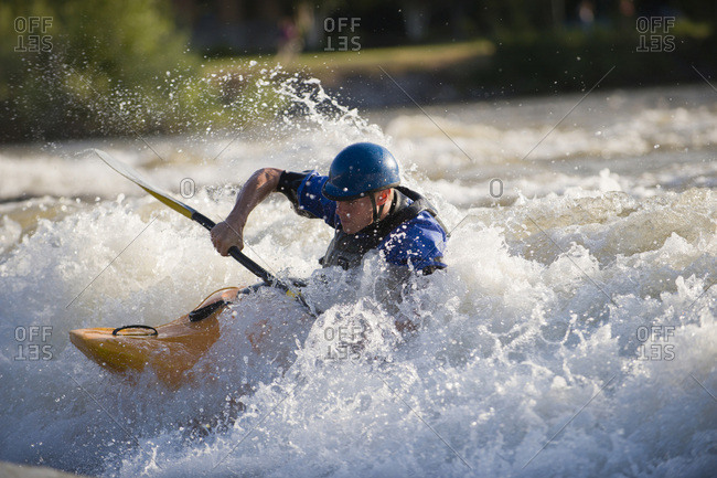 A male whitewater kayaker playboats on the Missoula playwave.