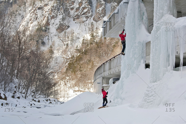 A man is belayed while climbing an ice pillar on a highway in Sounkyo Gorge, Daisetsuzan National Park, Hokkaido, Japan.