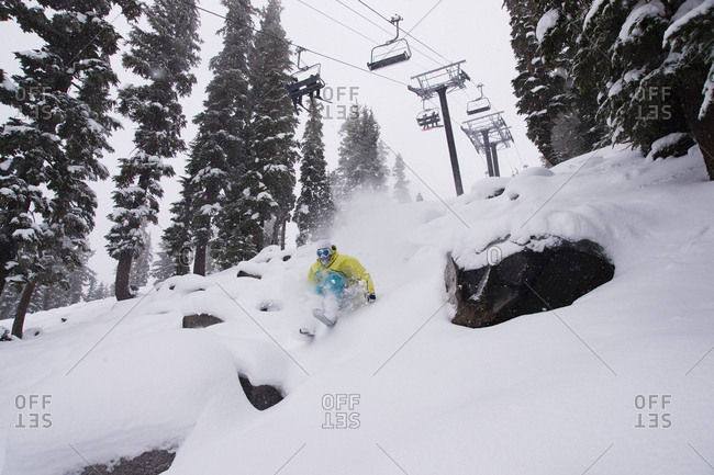 A man skiing powder snow beneath a chairlift at Northstar at Tahoe in California