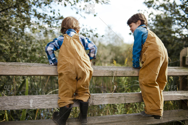 Young boys climbing a wooden fence.