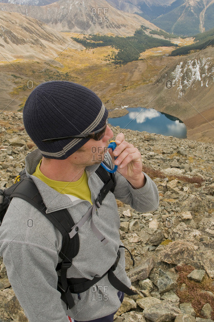 A man stops to hydrate while hiking along an alpine ridge on a crisp fall day.
