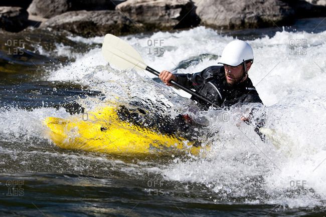 A male kayaker in a playboat paddles on the Clark Fork River, Missoula, Montana.