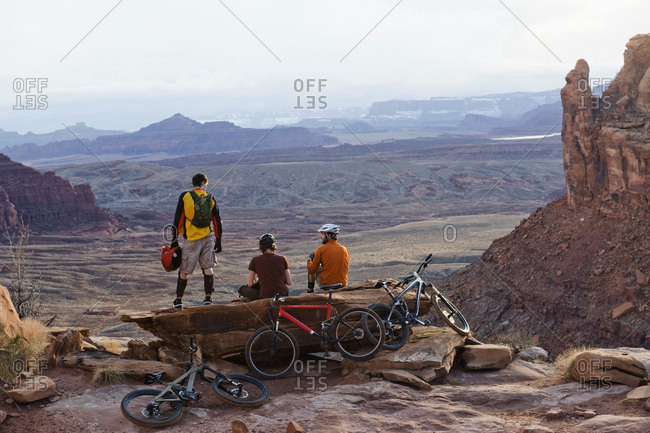 Three young men overlook a canyon after biking up the Amasa Back Trail, Moab, UT.