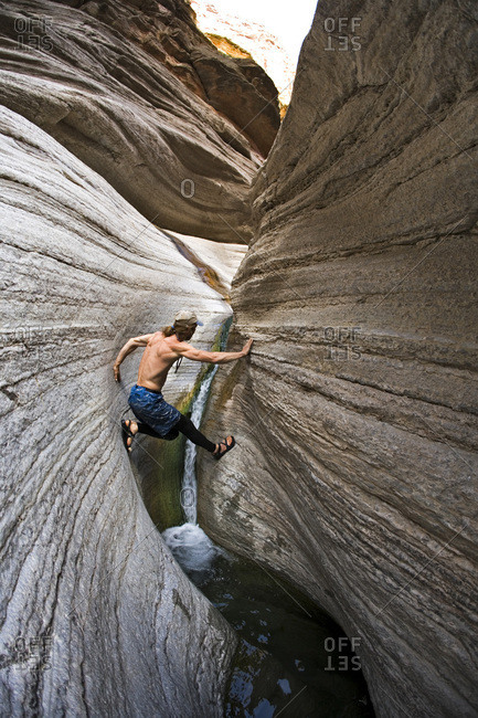 Man scrambling in narrow desert canyon, Grand Canyon, Arizona