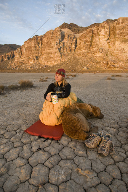 A woman and her dog camped on a dry, cracked lake bed, Delta, Utah.