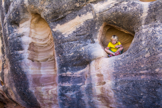 A young girl  in sandstone alcove in the Needles District of Canyonlands National Park, Monticello, Utah.
