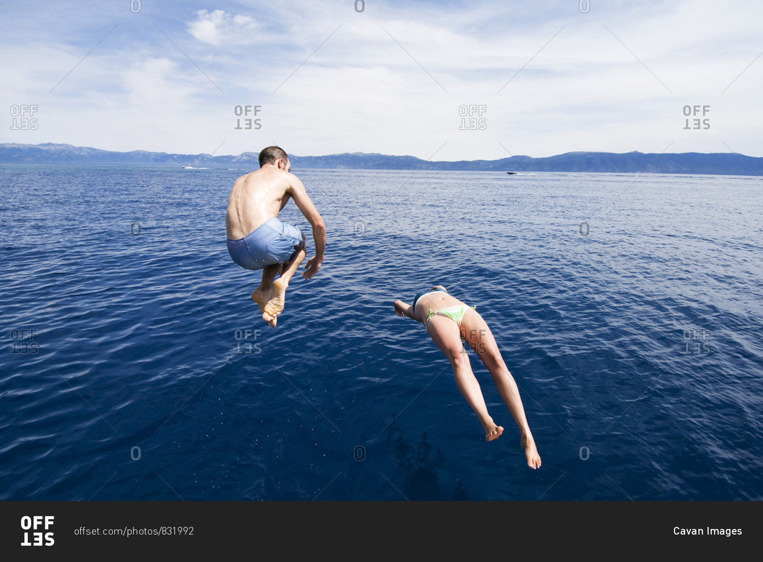 A young couple dive in the crystal blue water on a hot summer day in Lake Tahoe, Nevada.