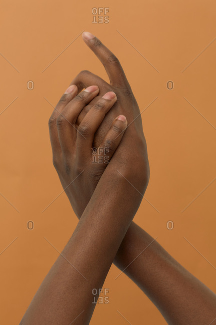 Male hands twisted together on light brown background