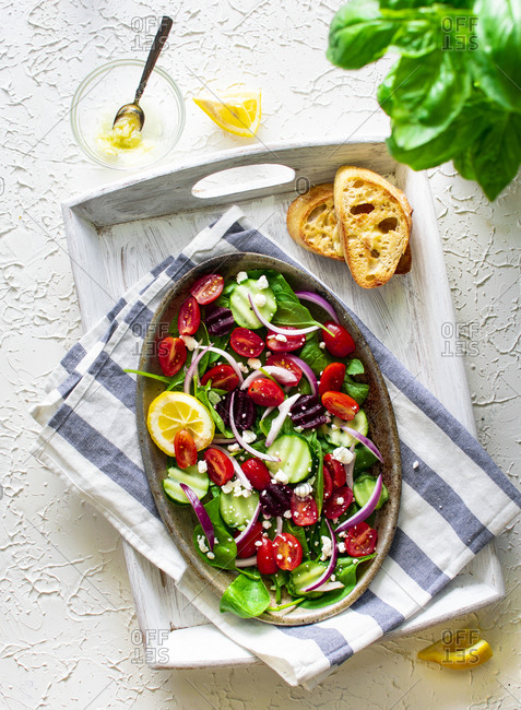 Colorful summer salad with cherry tomatoes, cucumbers, greens, onions and cheese with toasted bread on side