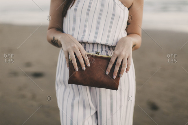 Beautiful young woman is walking in green mini dress and high heels, holding  gold clutch purse, looking at camera and smiling. Side view. Full length  Stock Photo - Alamy