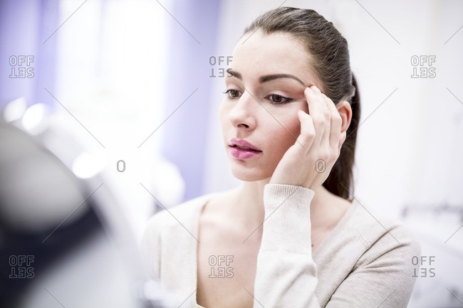 Woman looking in mirror in clinic.