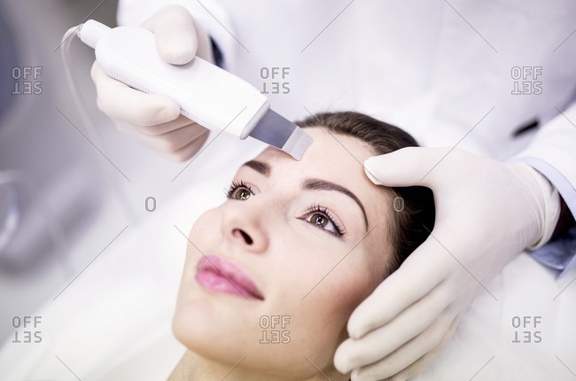 Young woman receiving facial microdermabrasion treatment in clinic, close-up. The cosmetic procedure uses micro crystals to remove dead skin cells. This exfoliating treatment can stimulate the production of collagen and help improve fine lines and acne sc