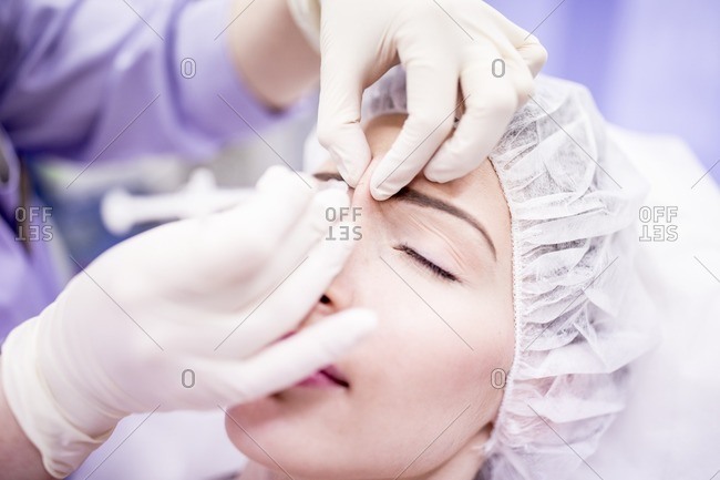 Beauty technician injecting botox into a woman's face. Botox is used medically to treat certain muscular conditions and cosmetically to reduce wrinkles. It is made from a neurotoxin called botulinum toxin and works by temporarily paralyzing muscles.