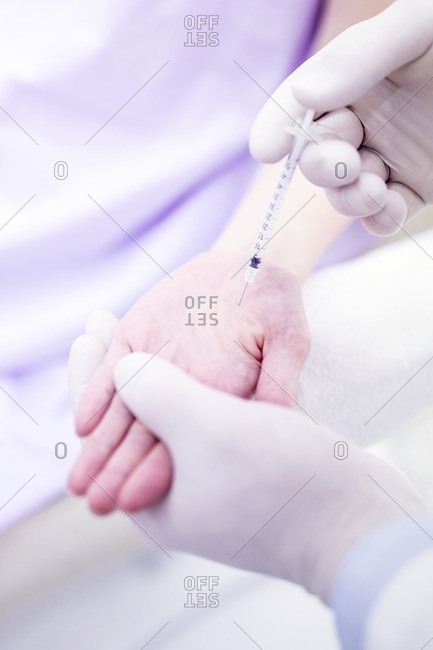 Dermatologist injecting botox into the palm of the hand to treat excessive sweating, close-up.