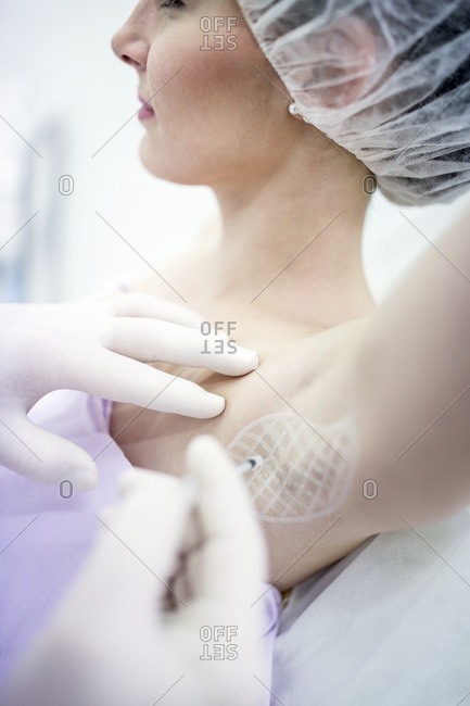 Dermatologist injecting botox in underarm to treat excessive sweating, close-up.