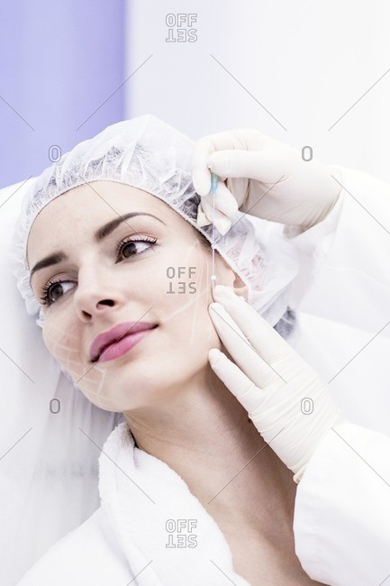 Dermatologist applying thread applicator on woman's face, close-up.