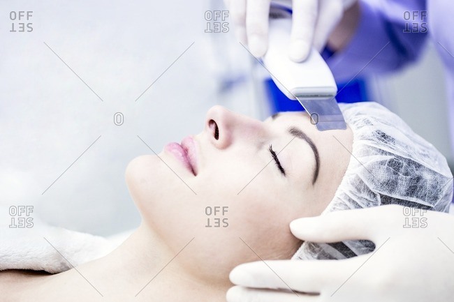 Young woman receiving facial microdermabrasion treatment in clinic, close-up. Young woman receiving facial microdermabrasion treatment in clinic, close-up. The cosmetic procedure uses micro crystals to remove dead skin cells. This exfoliating treatment can stimulate the production of collagen and help improve fine lines and acne scarring.