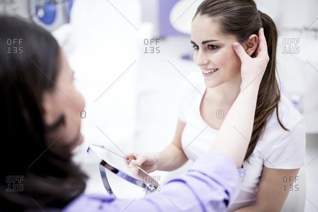 Dermatologist examining patient's facial skin, close-up.