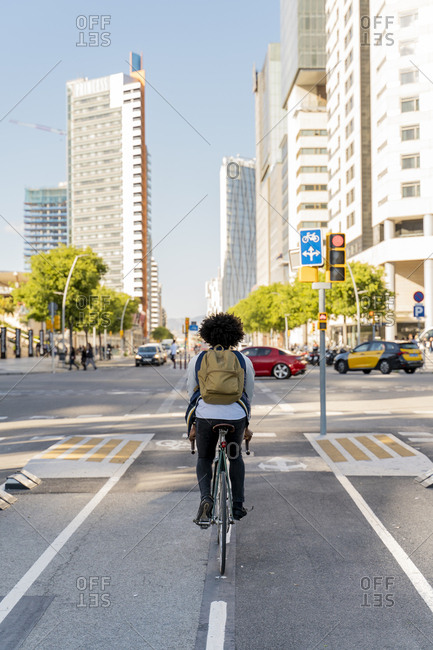 Rear view of casual businessman on bicycle in the city- Barcelona- Spain