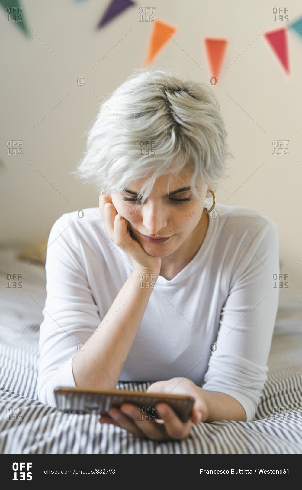 Woman using cell phone on bed at home