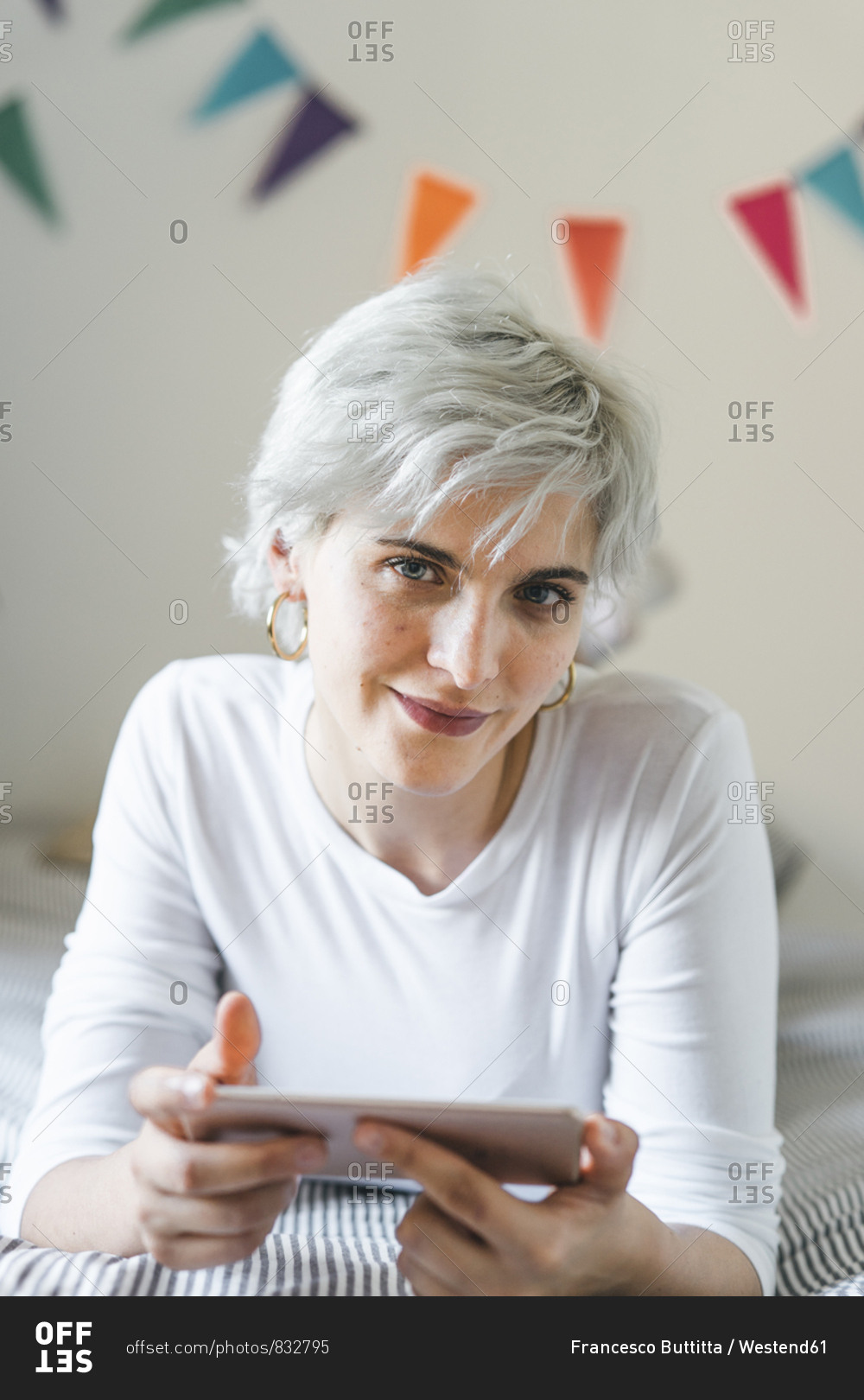 Portrait of smiling woman using cell phone on bed at home