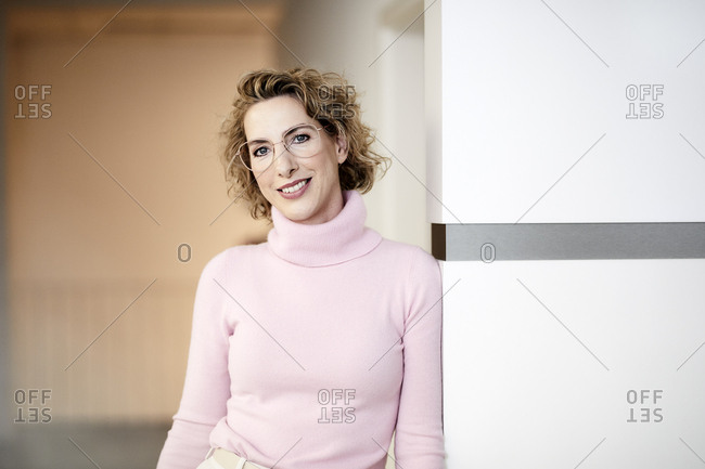 Portrait of smiling businesswoman wearing pink turtleneck pullover and glasses